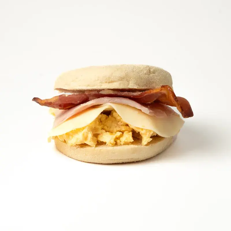 Muffin americano con huevo revuelto, queso, jamón y bacon