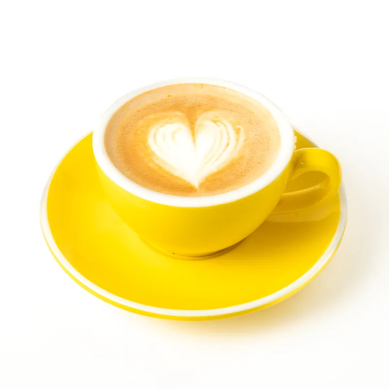Flat white con un corazón dibujado en la espuma, en taza amarilla con platillo