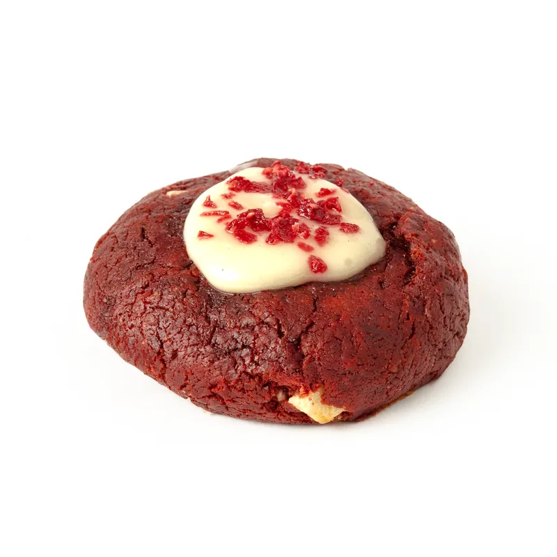 Cookie red velvet de masa roja con crema blanca y trocitos rojos por encima