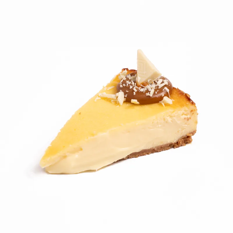 Porción de tarta de queso de Milkybar con un toque de crema, una onza y virutas de chocolate blanco
